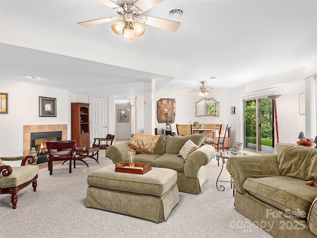 living room featuring a tiled fireplace, light carpet, and ceiling fan