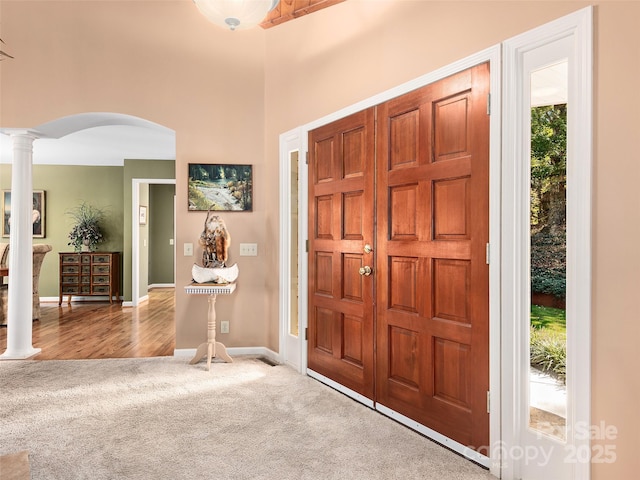 foyer entrance featuring light carpet and ornate columns