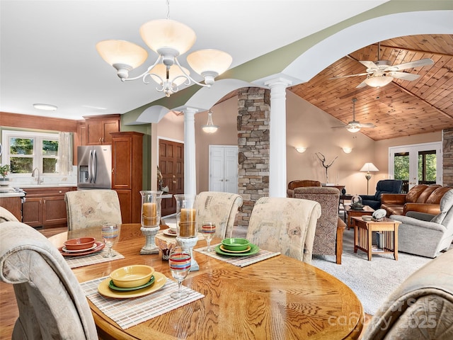 dining room featuring lofted ceiling, wood ceiling, sink, ornate columns, and ceiling fan with notable chandelier