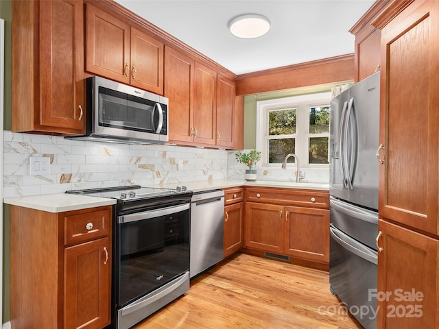 kitchen with sink, backsplash, stainless steel appliances, and light hardwood / wood-style flooring