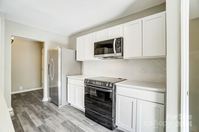 kitchen with stainless steel appliances, light hardwood / wood-style floors, white cabinetry, and tasteful backsplash