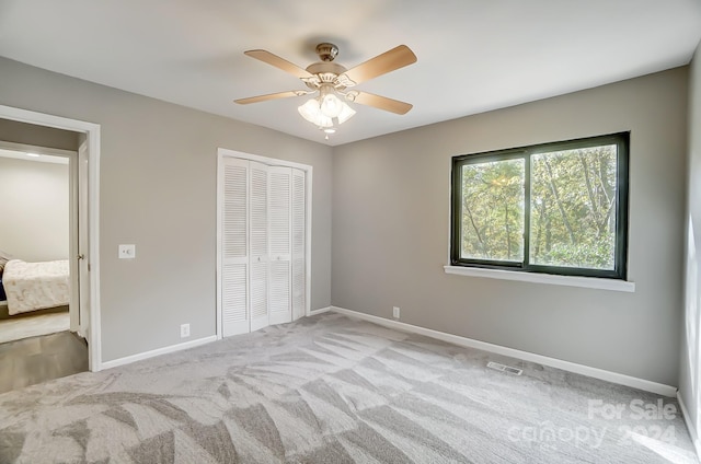 unfurnished bedroom featuring light colored carpet, ceiling fan, and a closet