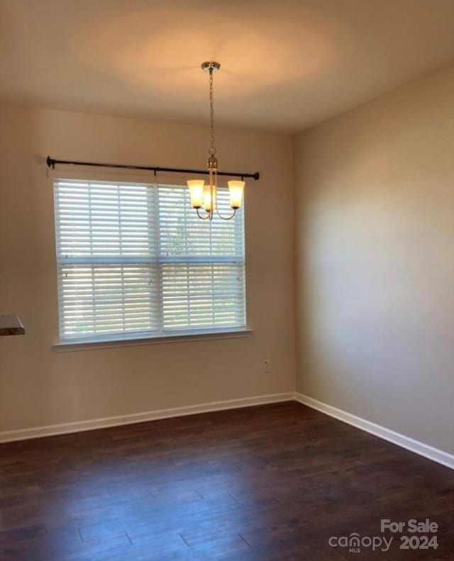 unfurnished room featuring dark hardwood / wood-style flooring and a chandelier