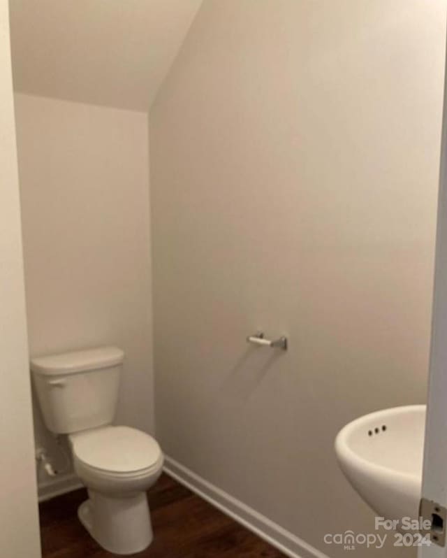 bathroom featuring sink, hardwood / wood-style floors, vaulted ceiling, and toilet