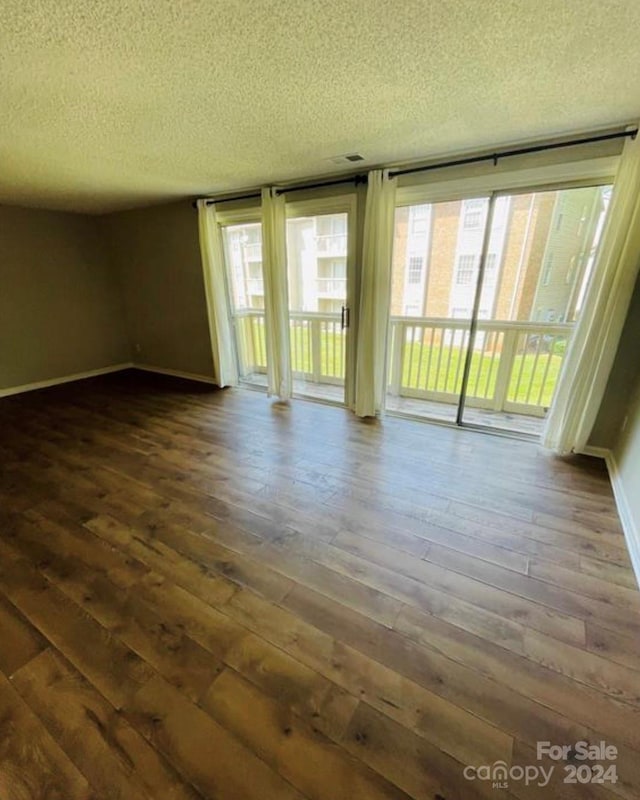 unfurnished room with a textured ceiling and dark hardwood / wood-style flooring