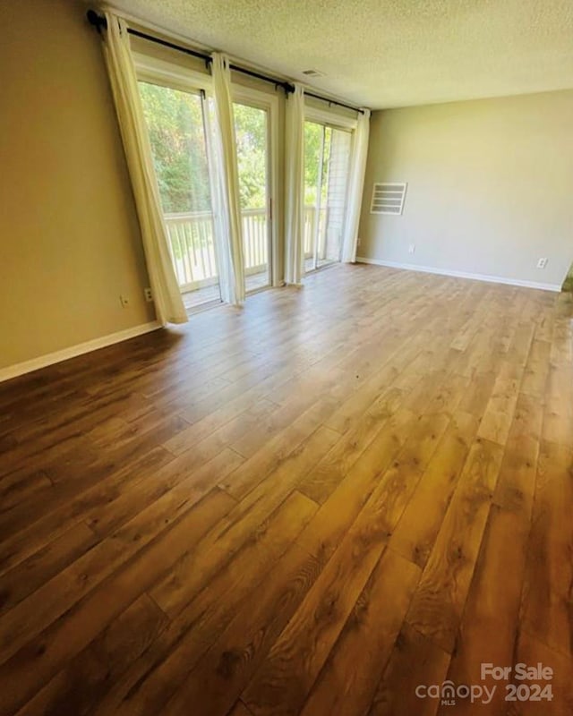 spare room featuring a textured ceiling and hardwood / wood-style floors