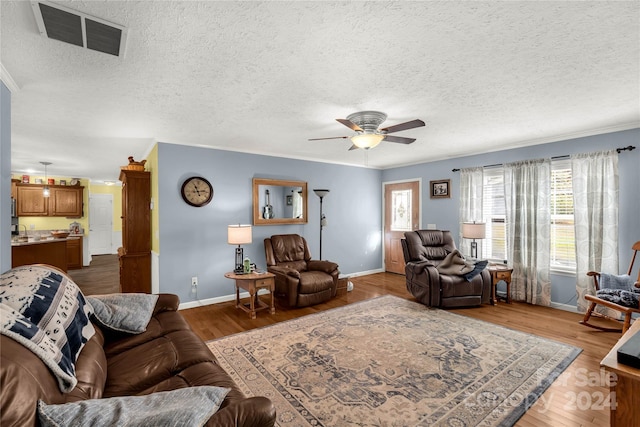 living room featuring ornamental molding, hardwood / wood-style floors, a textured ceiling, and ceiling fan