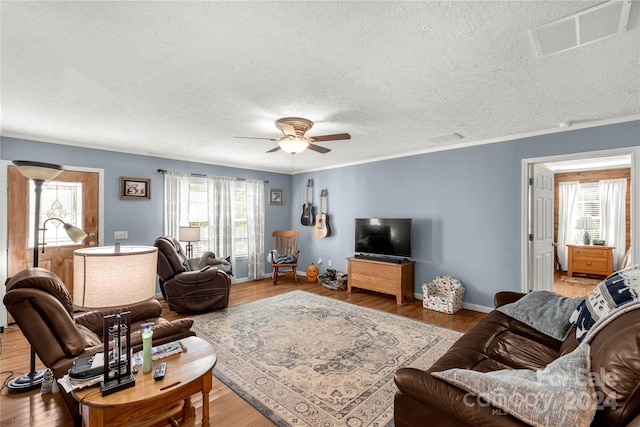 living room with ceiling fan, a healthy amount of sunlight, wood-type flooring, and a textured ceiling