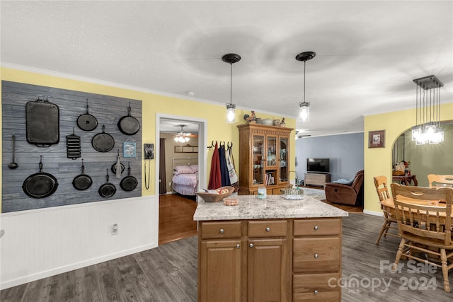 kitchen with hanging light fixtures, ornamental molding, light stone countertops, dark hardwood / wood-style flooring, and ceiling fan