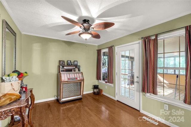 entryway with a textured ceiling, crown molding, wood-type flooring, and ceiling fan