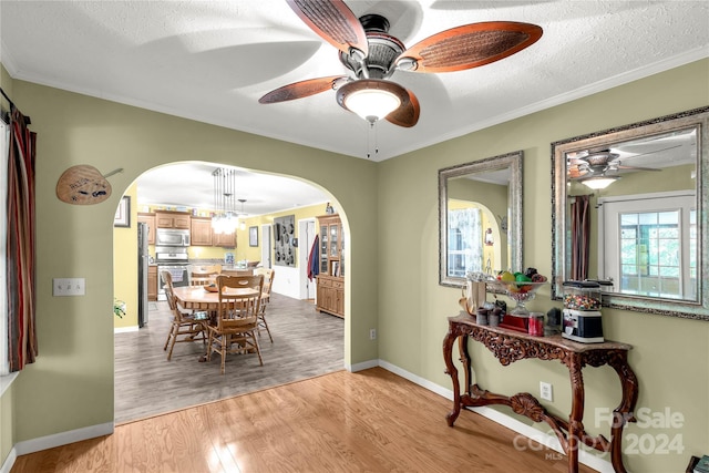 dining space with ornamental molding, a textured ceiling, light hardwood / wood-style floors, and ceiling fan