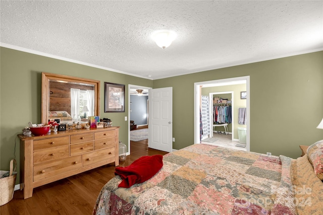 bedroom featuring a textured ceiling, a spacious closet, ornamental molding, dark hardwood / wood-style floors, and a closet