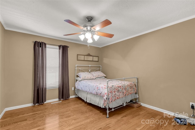 bedroom featuring ornamental molding, light wood-type flooring, and ceiling fan