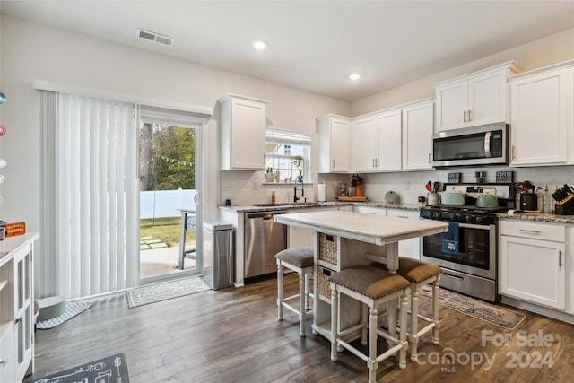 kitchen with tasteful backsplash, a kitchen breakfast bar, white cabinetry, stainless steel appliances, and dark wood-type flooring