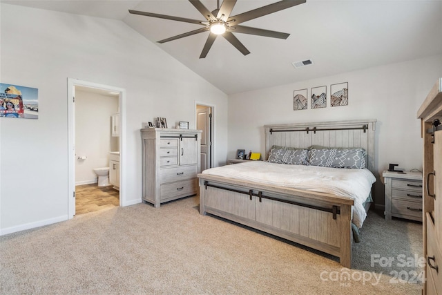 bedroom featuring ceiling fan, light carpet, vaulted ceiling, and ensuite bath