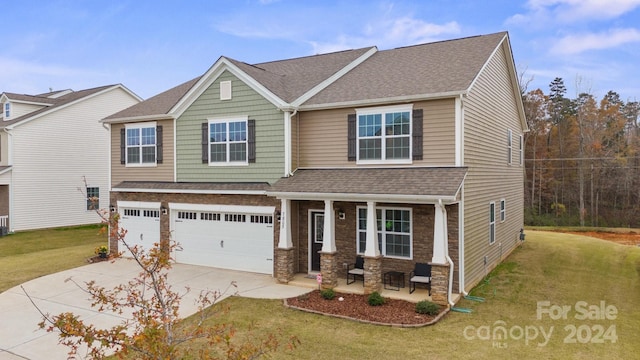 view of front of home with covered porch, a garage, and a front lawn