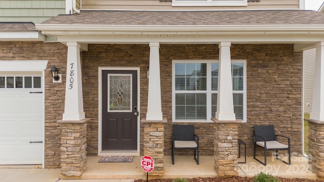 view of exterior entry featuring a garage and covered porch