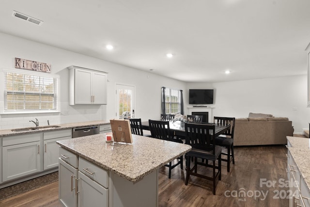 kitchen with dark hardwood / wood-style flooring, light stone counters, sink, and plenty of natural light