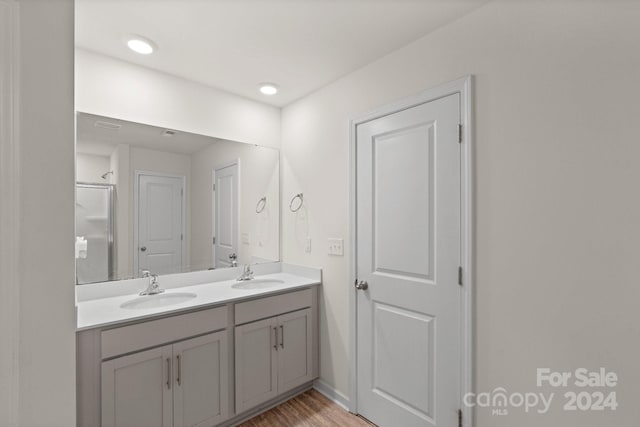 bathroom with hardwood / wood-style floors, vanity, and a shower with door