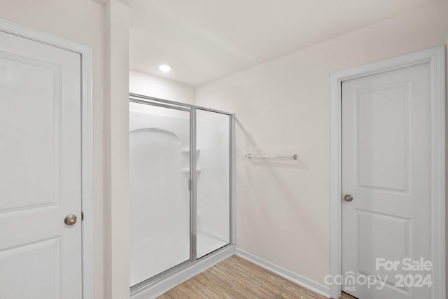 bathroom with hardwood / wood-style flooring and an enclosed shower