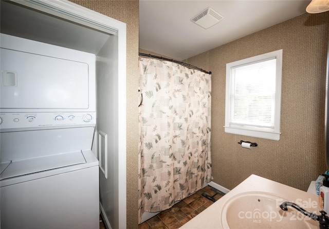 bathroom featuring vanity, walk in shower, stacked washer / dryer, and parquet flooring