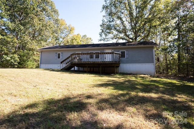 rear view of house with a wooden deck and a lawn