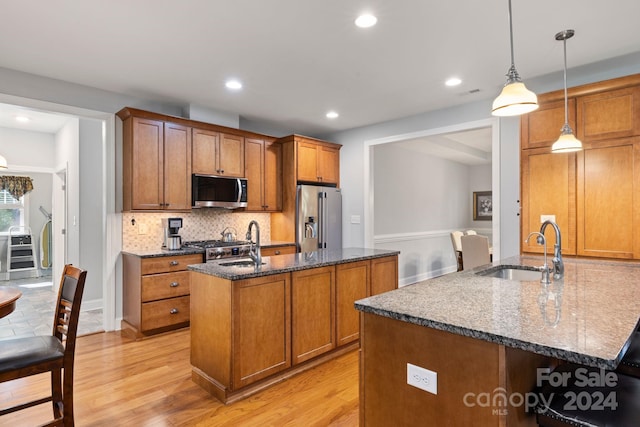 kitchen featuring pendant lighting, stainless steel appliances, sink, and light wood-type flooring