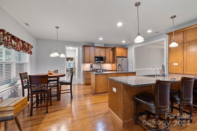 kitchen featuring light hardwood / wood-style flooring, decorative light fixtures, stainless steel appliances, and sink