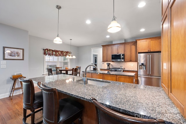 kitchen with decorative light fixtures, stainless steel appliances, sink, and dark hardwood / wood-style floors