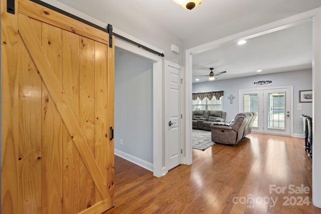 corridor with french doors, wood-type flooring, and a barn door