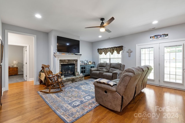 living room with a fireplace, light wood-type flooring, and ceiling fan