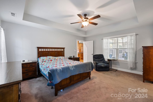 carpeted bedroom featuring a tray ceiling and ceiling fan