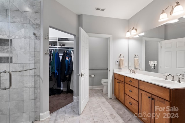 bathroom featuring a shower with door, vanity, toilet, and tile patterned floors