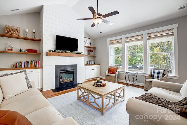 living room featuring a large fireplace, high vaulted ceiling, light hardwood / wood-style flooring, and ceiling fan