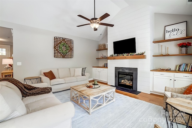 living room with ceiling fan, a fireplace, high vaulted ceiling, and light hardwood / wood-style flooring