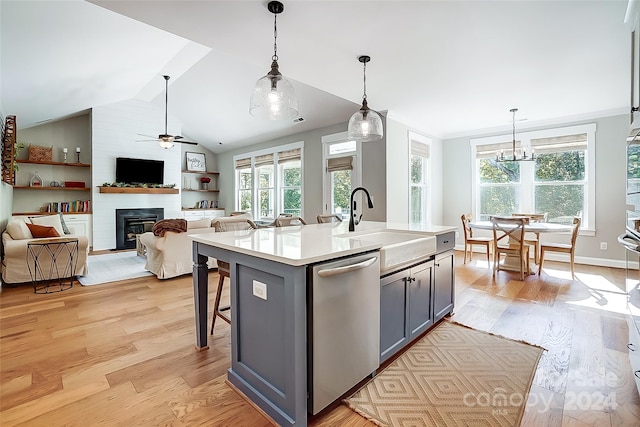 kitchen with dishwasher, decorative light fixtures, a center island with sink, and light wood-type flooring