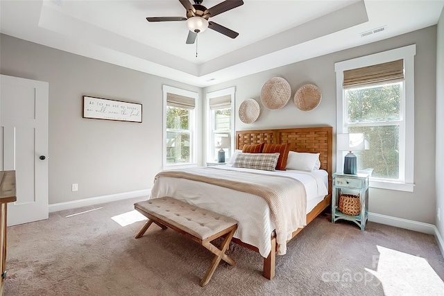 carpeted bedroom featuring a tray ceiling and ceiling fan