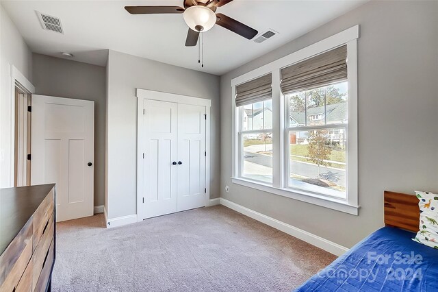 unfurnished bedroom with ceiling fan, light carpet, and a closet