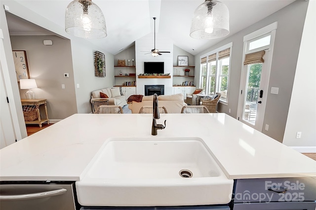 kitchen with dishwasher, light countertops, lofted ceiling, a fireplace, and a sink