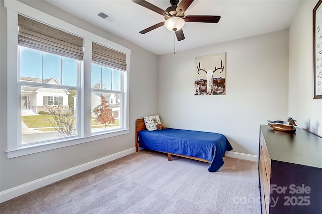 carpeted bedroom featuring a ceiling fan, visible vents, and baseboards