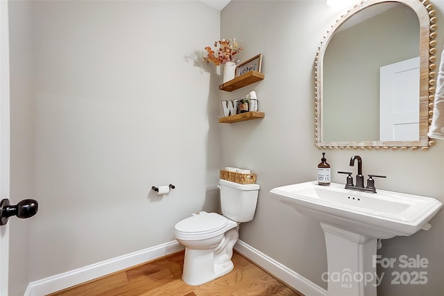 bathroom with a sink, baseboards, toilet, and wood finished floors