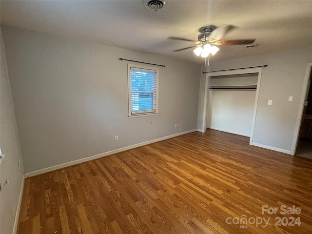 unfurnished bedroom featuring hardwood / wood-style floors, a closet, and ceiling fan