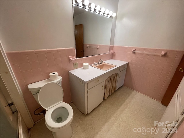 bathroom featuring tile walls, vanity, and toilet