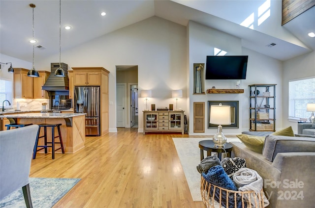 living room with sink, high vaulted ceiling, and light hardwood / wood-style flooring