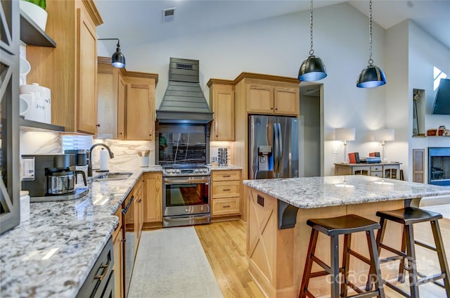 kitchen featuring sink, light wood-type flooring, appliances with stainless steel finishes, light stone counters, and high vaulted ceiling