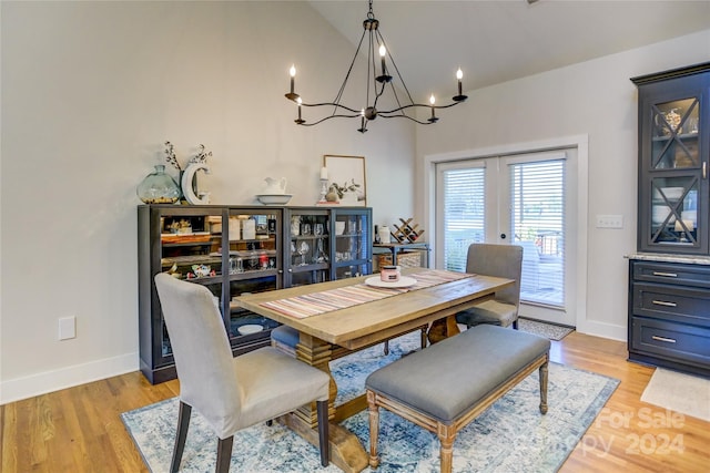 dining area with lofted ceiling, a notable chandelier, and light hardwood / wood-style floors