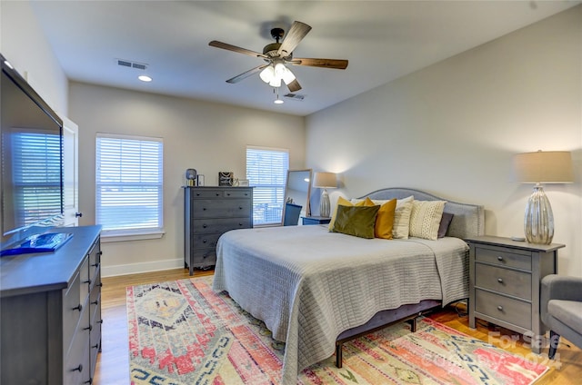 bedroom with ceiling fan, multiple windows, and light wood-type flooring