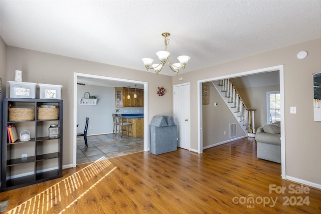 unfurnished dining area with an inviting chandelier, a textured ceiling, and hardwood / wood-style flooring