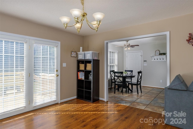 dining area with a textured ceiling, wood-type flooring, and ceiling fan with notable chandelier