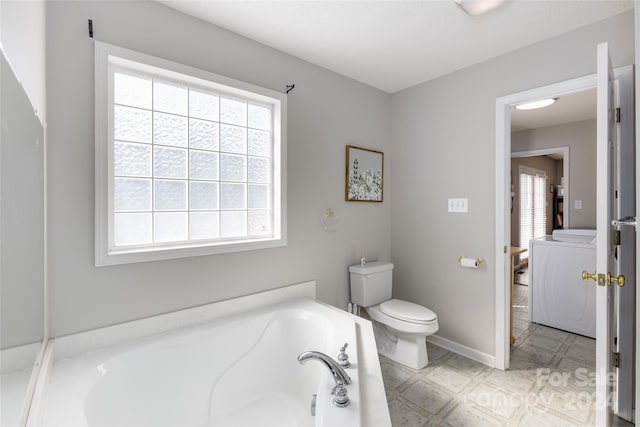 bathroom featuring plenty of natural light, toilet, and a washtub